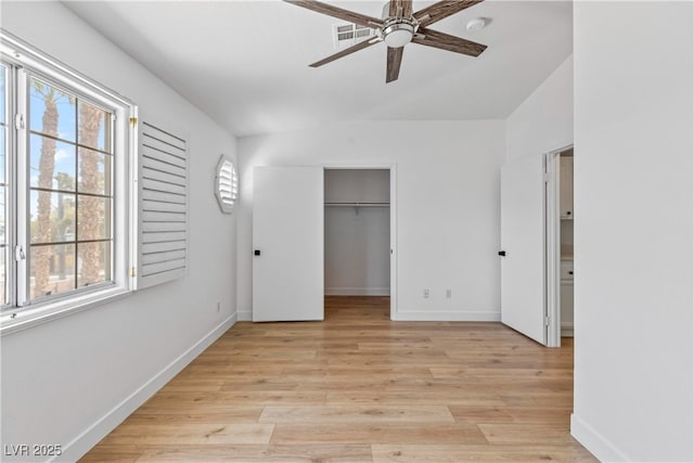 unfurnished bedroom with visible vents, light wood finished floors, a walk in closet, and baseboards