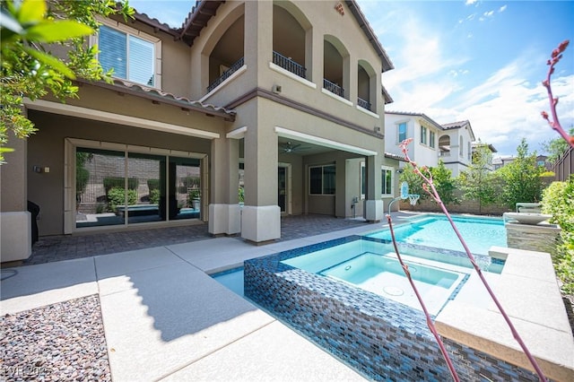 12018 Vento Forte Ave, Las Vegas, NV 89138 - back of house with stucco siding, a patio area, a tiled roof, a pool with connected hot tub, and a balcony