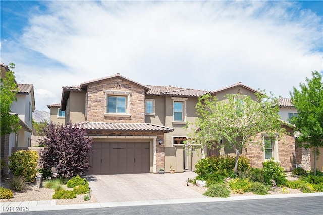 12018 Vento Forte Ave, Las Vegas, NV 89138 - view of front of house featuring a tile roof, stucco siding, an attached garage, stone siding, and driveway