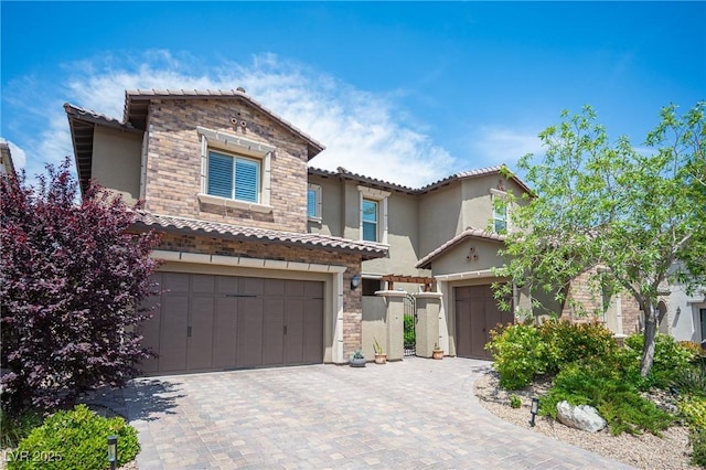 12018 Vento Forte Ave, Las Vegas, NV 89138 - mediterranean / spanish house featuring stucco siding, a garage, stone siding, a tiled roof, and decorative driveway
