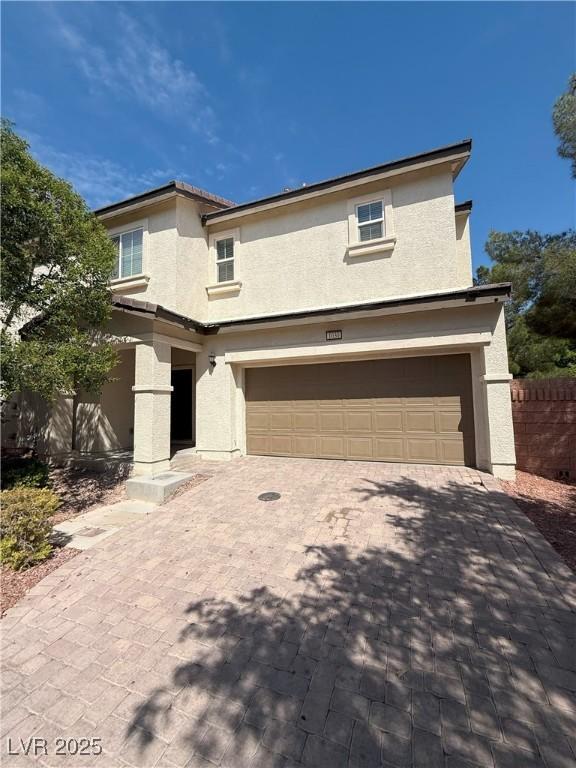 view of front facade featuring an attached garage, stucco siding, and driveway