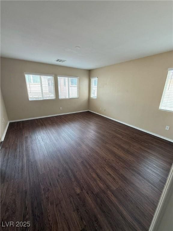 empty room with baseboards, dark wood-style floors, and a wealth of natural light