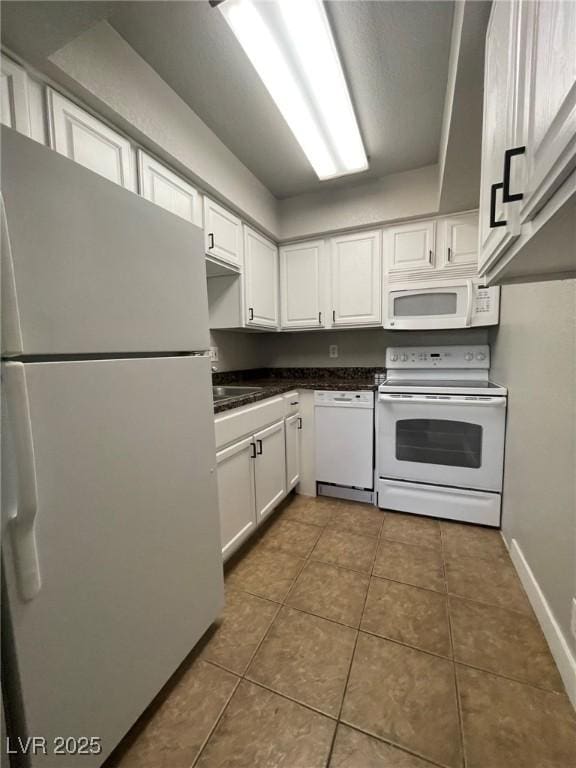 kitchen with dark countertops, white appliances, baseboards, white cabinetry, and tile patterned floors