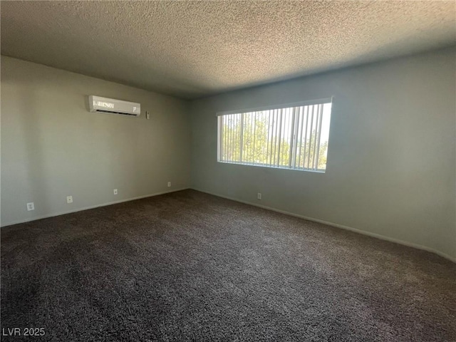 spare room featuring an AC wall unit, a textured ceiling, carpet floors, and baseboards