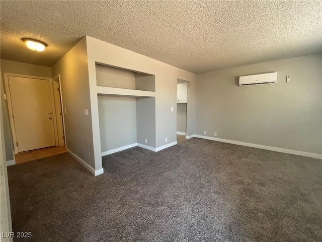unfurnished bedroom with an AC wall unit, a textured ceiling, dark carpet, baseboards, and a closet