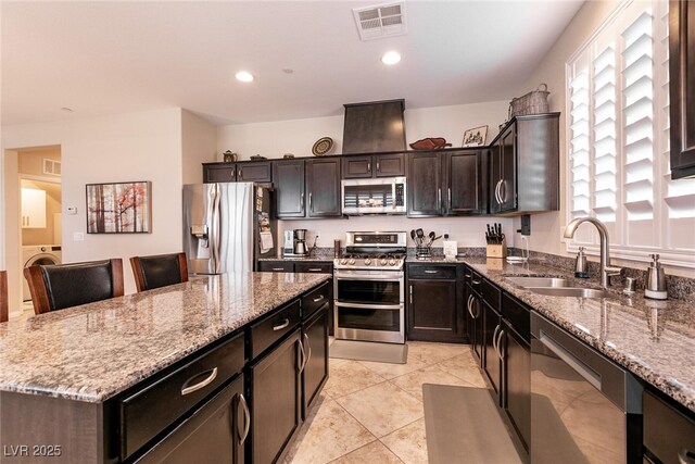 63 Via Di Mello, Henderson, NV 89011 - kitchen with appliances with stainless steel finishes, a sink, washer / dryer, a kitchen island, and stone countertops