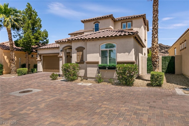 63 Via Di Mello, Henderson, NV 89011 - mediterranean / spanish-style house featuring stucco siding, an attached garage, a tile roof, and decorative driveway