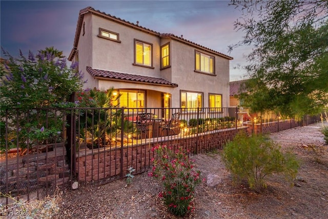 63 Via Di Mello, Henderson, NV 89011 - back of house at dusk with stucco siding, a tiled roof, and fence