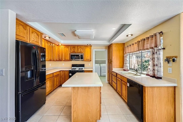 4 Bishopsgate Ter, Henderson, NV 89074 - kitchen featuring black appliances, separate washer and dryer, a sink, a tray ceiling, and a center island