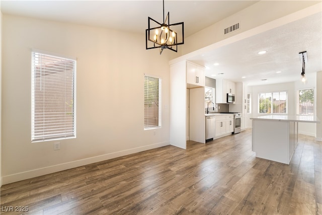 2505 Showcase Dr, Las Vegas, NV 89134 - kitchen with appliances with stainless steel finishes, white cabinetry, a chandelier, wood finished floors, and recessed lighting