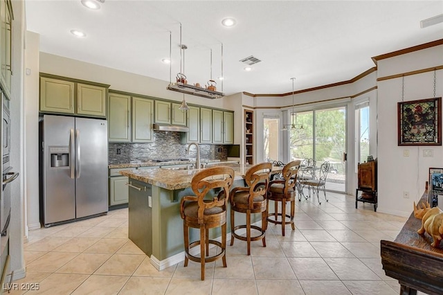 kitchen featuring visible vents, under cabinet range hood, stainless steel fridge with ice dispenser, backsplash, and green cabinets