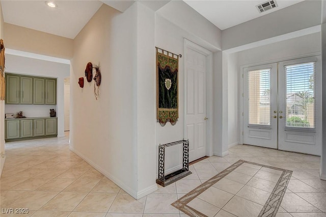 foyer entrance with light tile patterned floors, baseboards, visible vents, and french doors