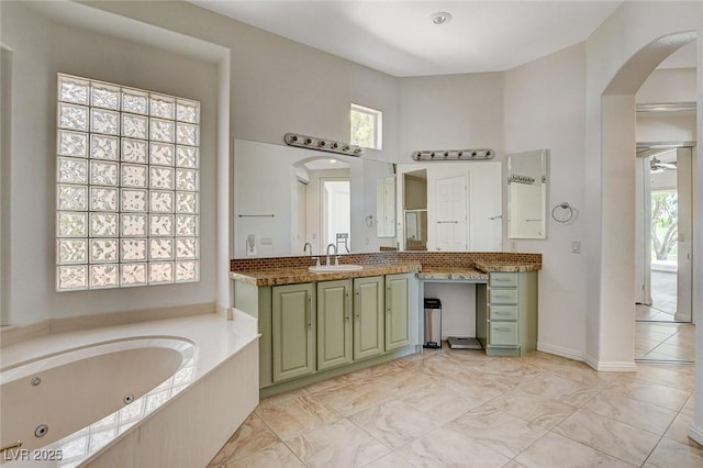 full bathroom with a towering ceiling, a whirlpool tub, and vanity
