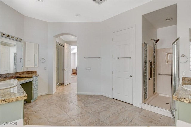full bath featuring a sink, marble finish floor, two vanities, and a shower stall