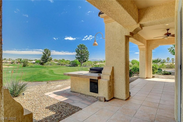 view of patio featuring a ceiling fan, view of golf course, and an outdoor kitchen