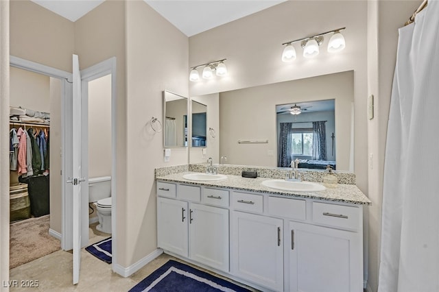 ensuite bathroom with double vanity, a sink, ensuite bath, and toilet