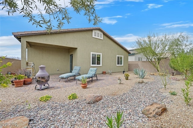 rear view of property featuring fence, a patio area, and stucco siding