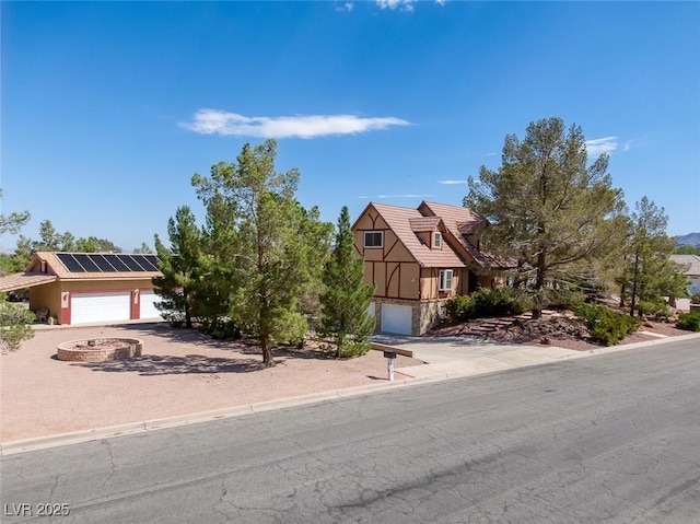 view of front of property featuring driveway, solar panels, a tile roof, a garage, and stone siding