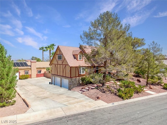 english style home with concrete driveway, stucco siding, stone siding, and a garage