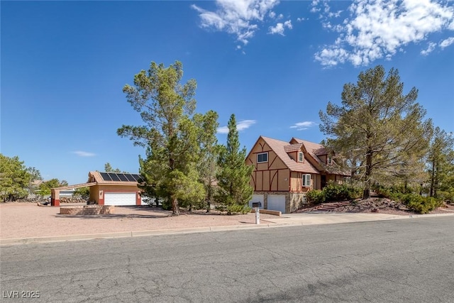 view of front of house featuring a tile roof, an attached garage, roof mounted solar panels, and stucco siding
