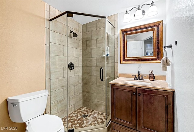 bathroom with vanity, a shower stall, and toilet
