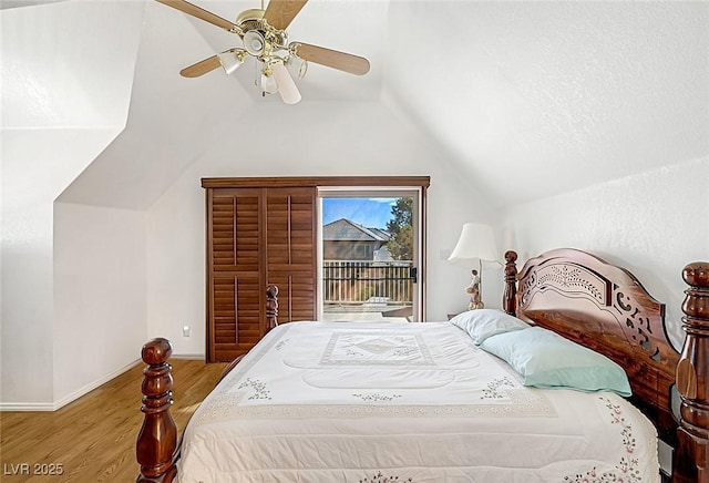 bedroom featuring a ceiling fan, access to exterior, wood finished floors, baseboards, and lofted ceiling