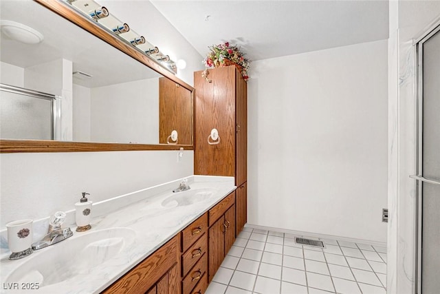full bath with a sink, tile patterned flooring, a shower with shower door, and visible vents