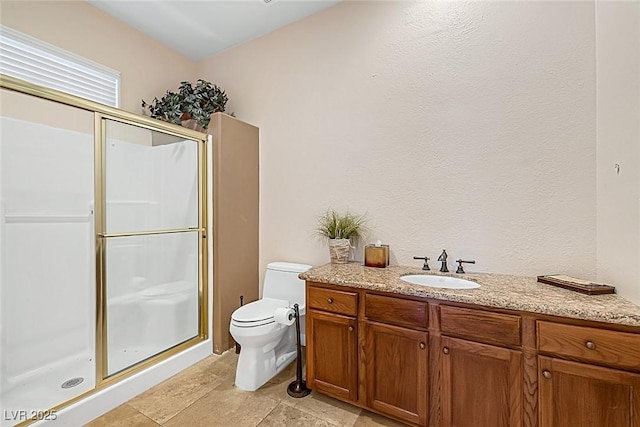 full bath featuring vanity, stone finish flooring, a stall shower, and toilet