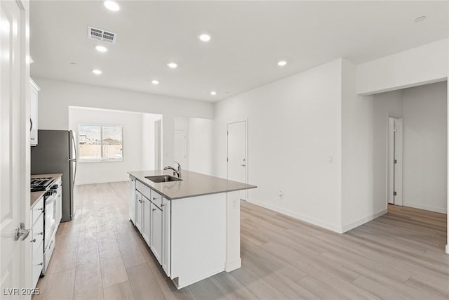 2739 Avril Point St, Las Vegas, NV 89156 - kitchen with a sink, a center island with sink, light wood-type flooring, visible vents, and gas range