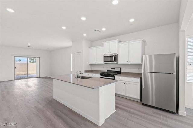 2739 Avril Point St, Las Vegas, NV 89156 - kitchen with appliances with stainless steel finishes, light wood-style flooring, a sink, white cabinetry, and an island with sink