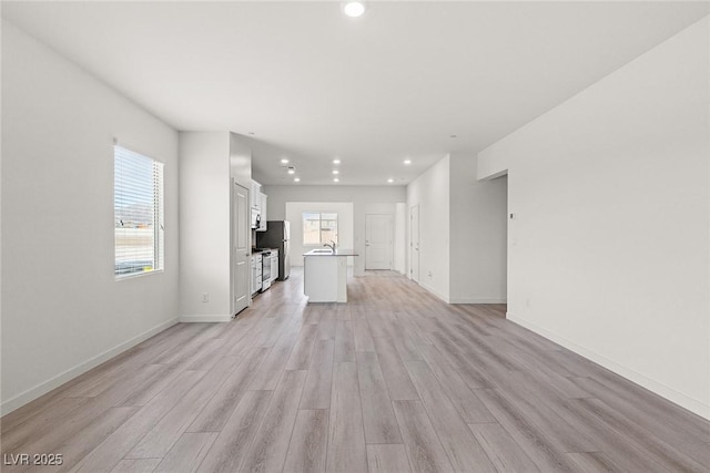 2739 Avril Point St, Las Vegas, NV 89156 - unfurnished living room featuring light wood-style flooring, baseboards, a sink, and recessed lighting
