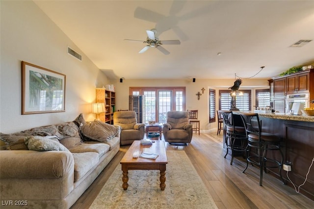 living room featuring ceiling fan, light wood-type flooring, and visible vents