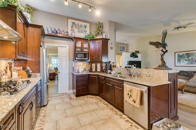 kitchen with backsplash, appliances with stainless steel finishes, light stone counters, a peninsula, and open floor plan
