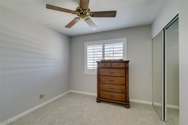 bedroom featuring baseboards, ceiling fan, a closet, and light colored carpet
