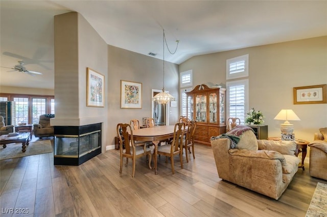 dining area featuring a multi sided fireplace, wood finished floors, and visible vents