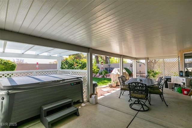 view of patio featuring a hot tub, outdoor dining space, and a fenced backyard