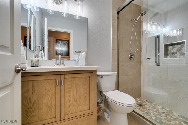 bathroom featuring vanity, a tile shower, and toilet