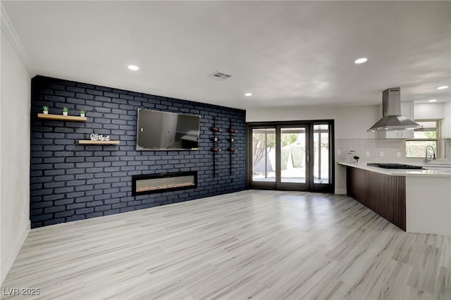 unfurnished living room with a wealth of natural light, wood finished floors, and visible vents
