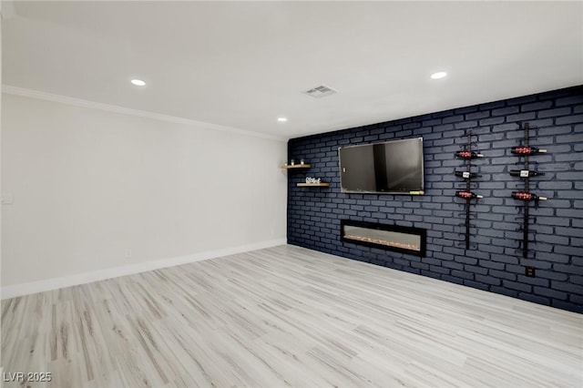 unfurnished living room featuring brick wall, a fireplace, wood finished floors, and visible vents