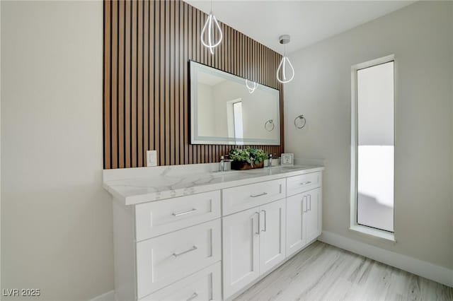 bathroom with baseboards, double vanity, and wood finished floors