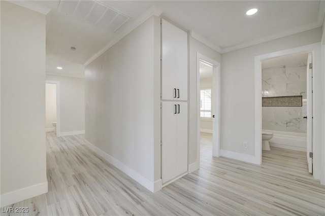 hall featuring baseboards, visible vents, ornamental molding, and light wood finished floors