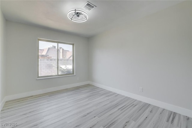empty room featuring baseboards, wood finished floors, and visible vents