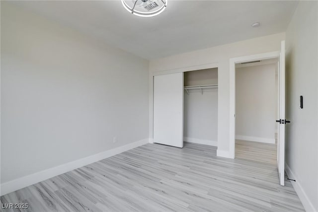 unfurnished bedroom featuring a closet, baseboards, and light wood-type flooring