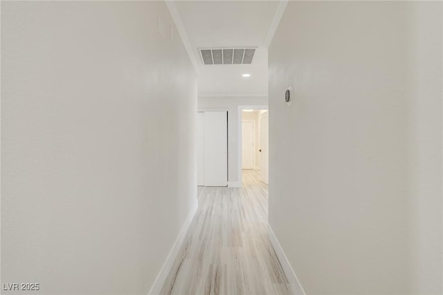 hall with baseboards, ornamental molding, light wood-style flooring, and visible vents