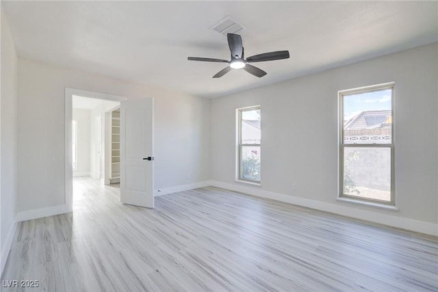 empty room with visible vents, a ceiling fan, light wood finished floors, and baseboards