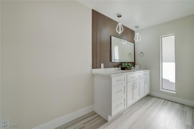full bath featuring baseboards, double vanity, and wood finished floors