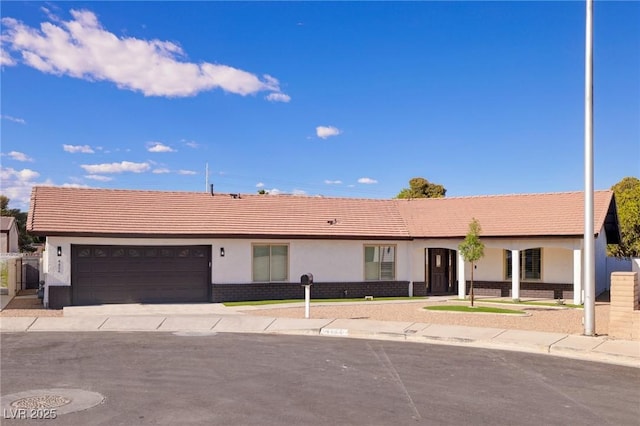 ranch-style home featuring a garage, stucco siding, a tiled roof, and driveway