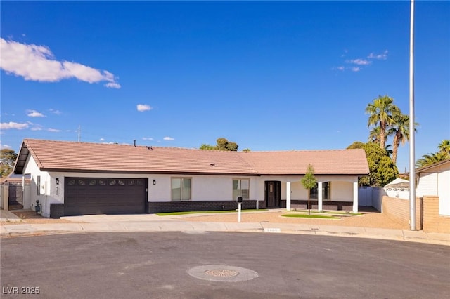 ranch-style home featuring a tiled roof, an attached garage, fence, and stucco siding