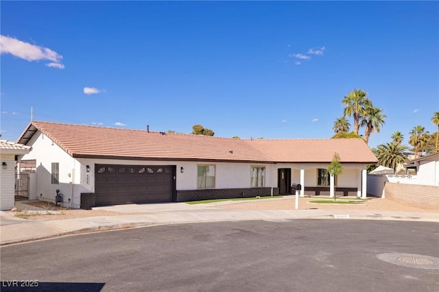 single story home with a garage, fence, a tiled roof, and stucco siding