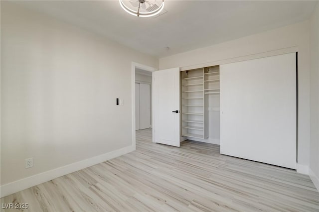 unfurnished bedroom featuring baseboards, wood finished floors, and a closet